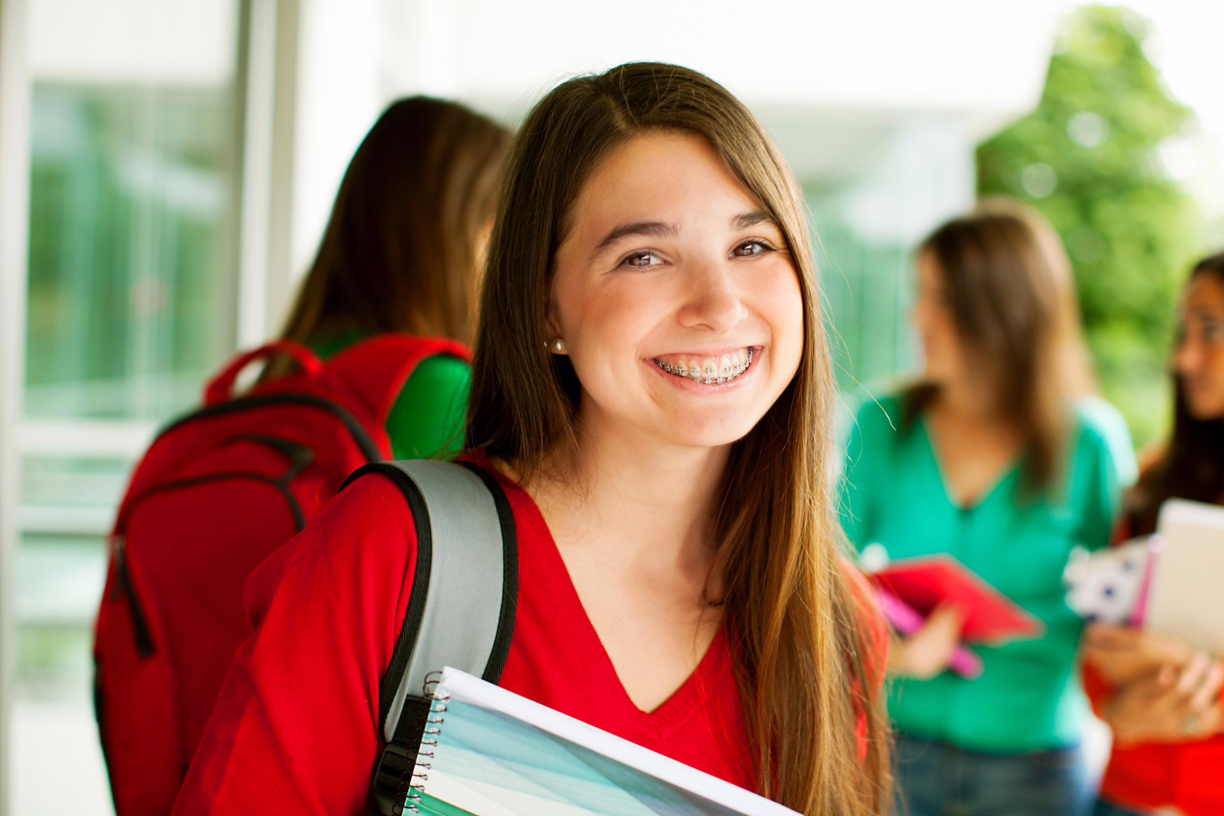 Smiling teen girl with braces and a red backpack, an orthodontic patient in Leesburg